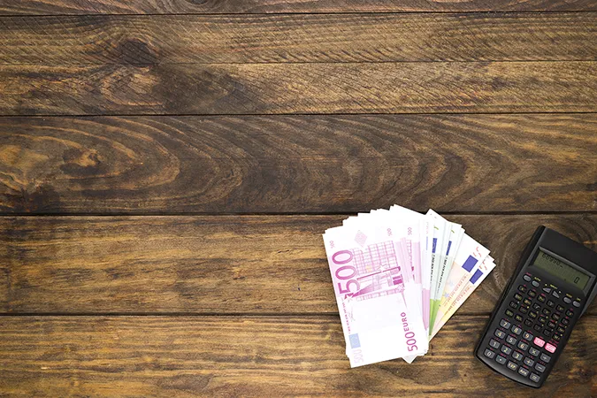Billets de banque euros et calculatrice sur une table en bois - Image designed by Freepik.com